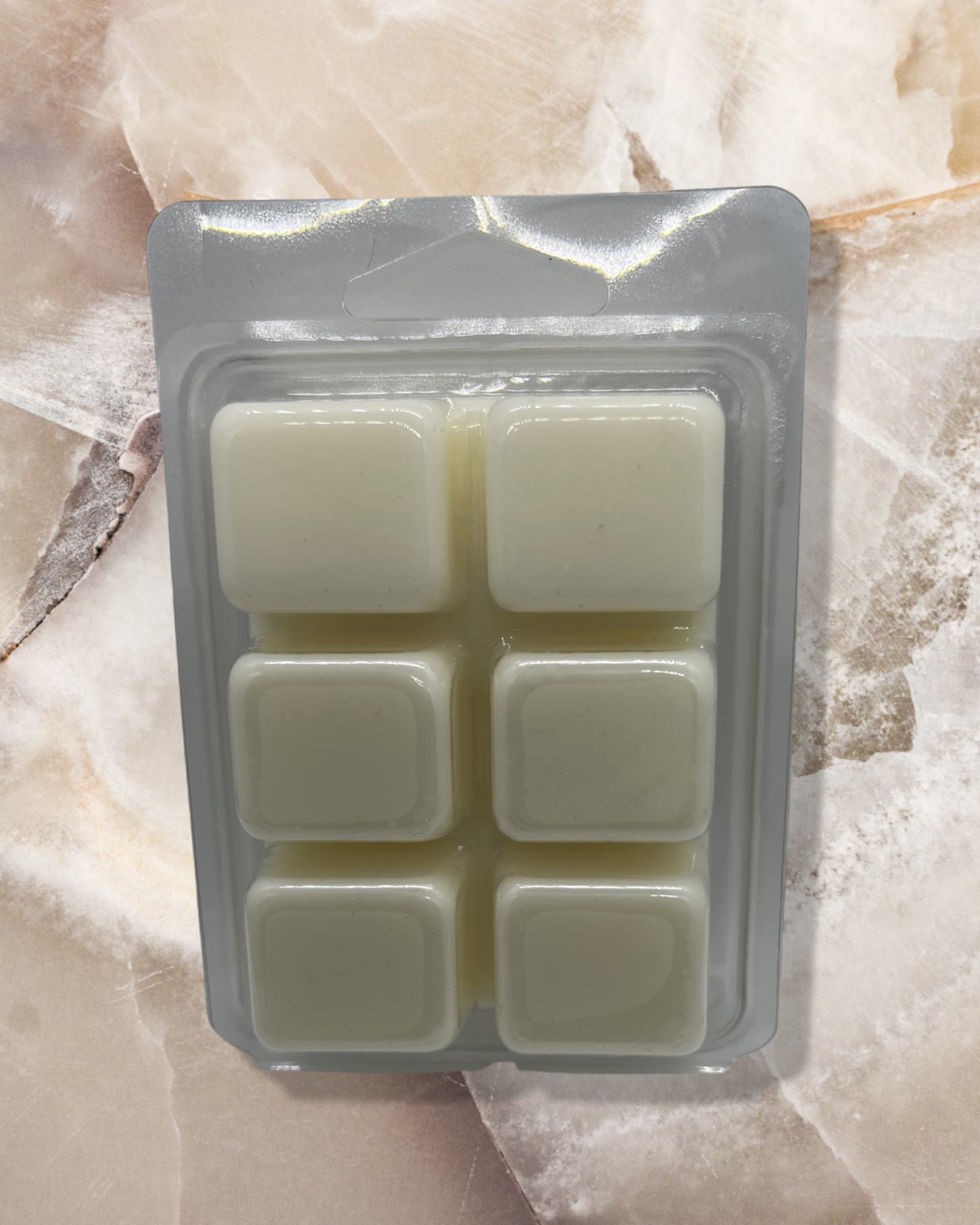 Vanilla Geur wax melts in creamy ivory color, presented in a clear plastic clamshell container with 6 perfectly-formed cubes. Premium scented wax melts displayed on a textured marble surface, offering a warm and versatile vanilla fragrance by Chatte Candles.