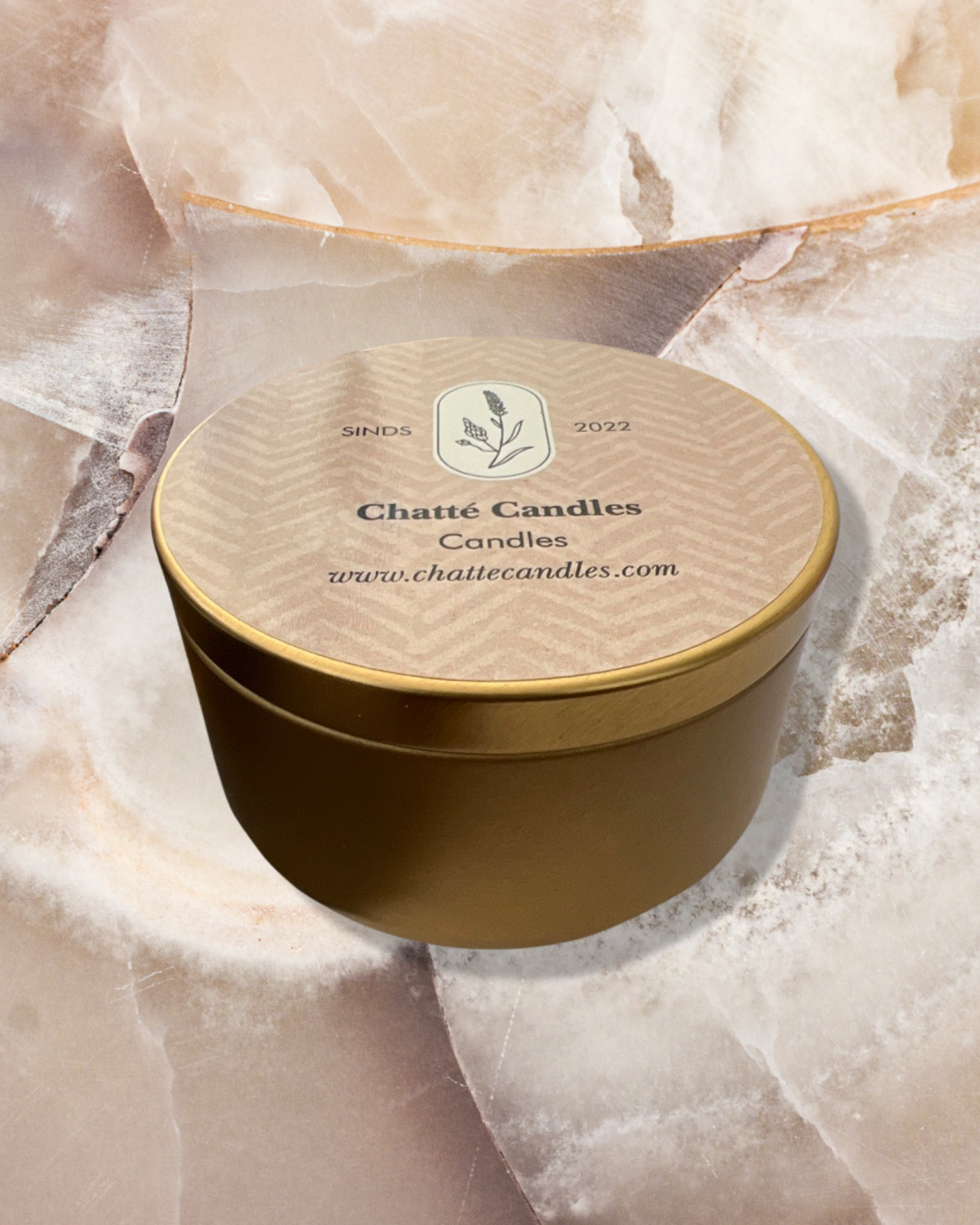 Chatte Peppermint luxury candle in elegant gold round tin container with beige textured lid featuring botanical logo, displayed on cream marble surface, perfect for fresh home fragrance and aromatherapy