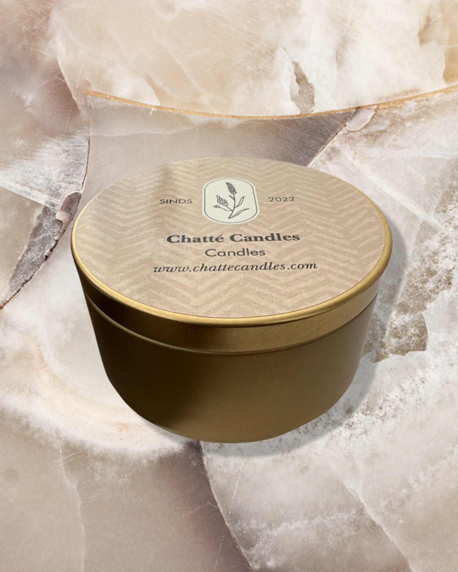 Chatte Peppermint luxury candle in elegant gold round tin container with beige textured lid featuring botanical logo, displayed on cream marble surface, perfect for fresh home fragrance and aromatherapy