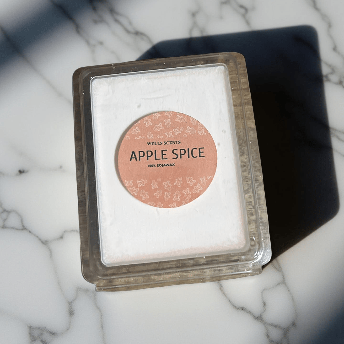 Apple Spice scented wax melt in clear clamshell packaging with soft pink label, by Chatté Candles on marble surface