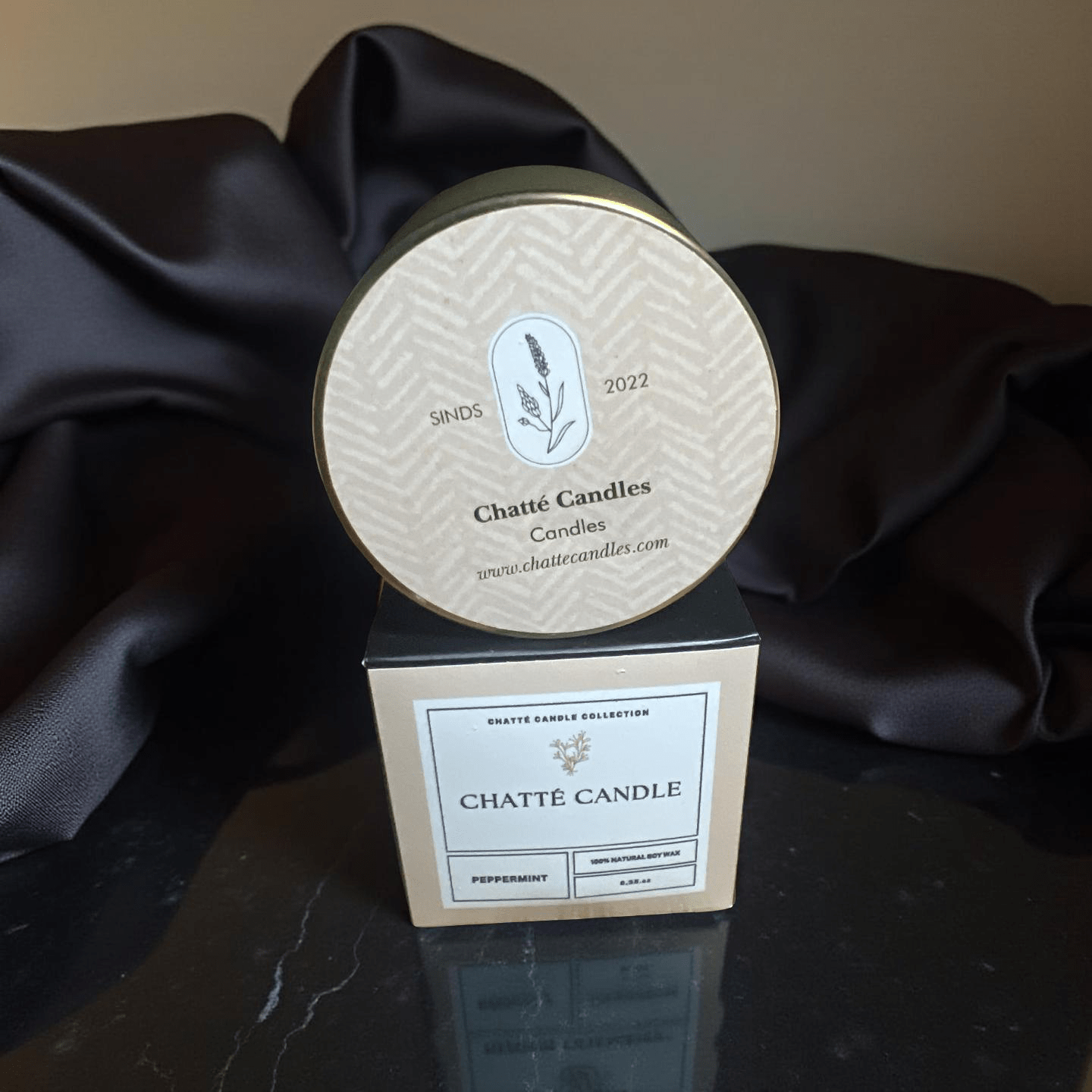 Chatté Peppermint candle in gold tin with botanical label on beige box, displayed on black marble surface by Mijn winkel